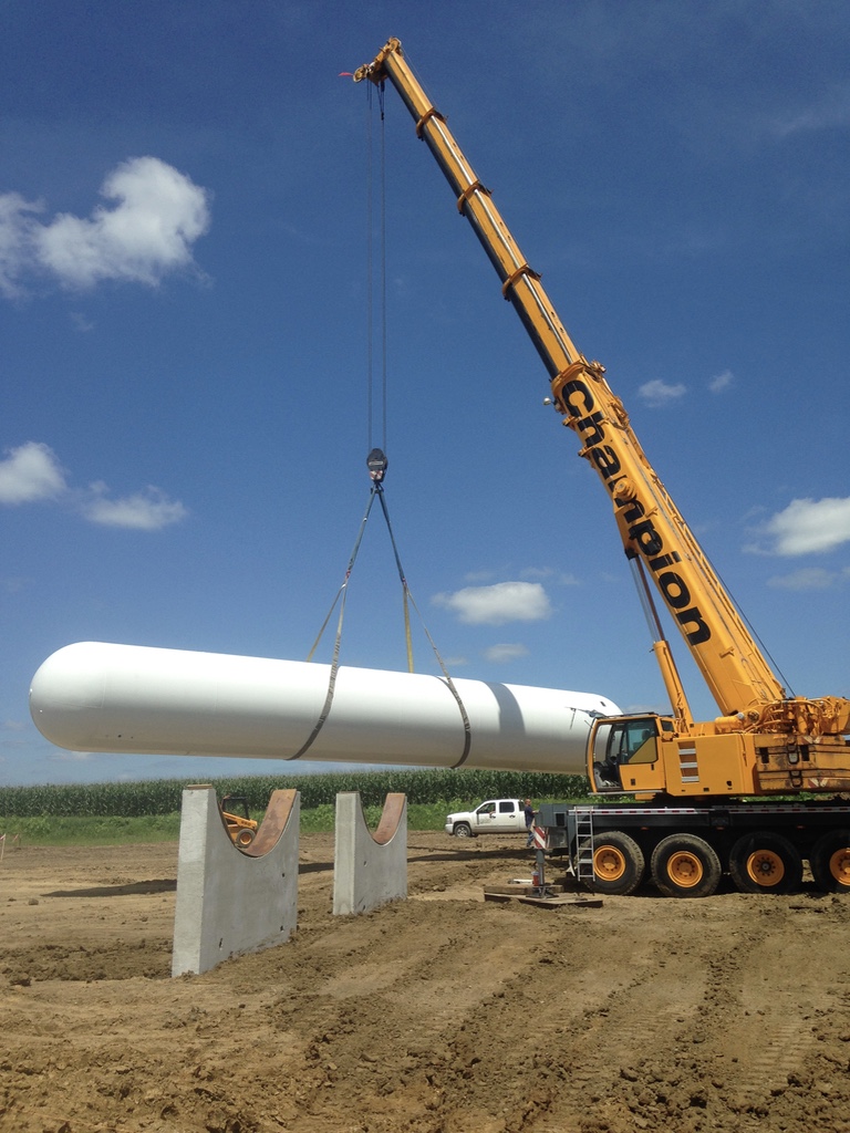 Champion crane setting a large white tank in the field